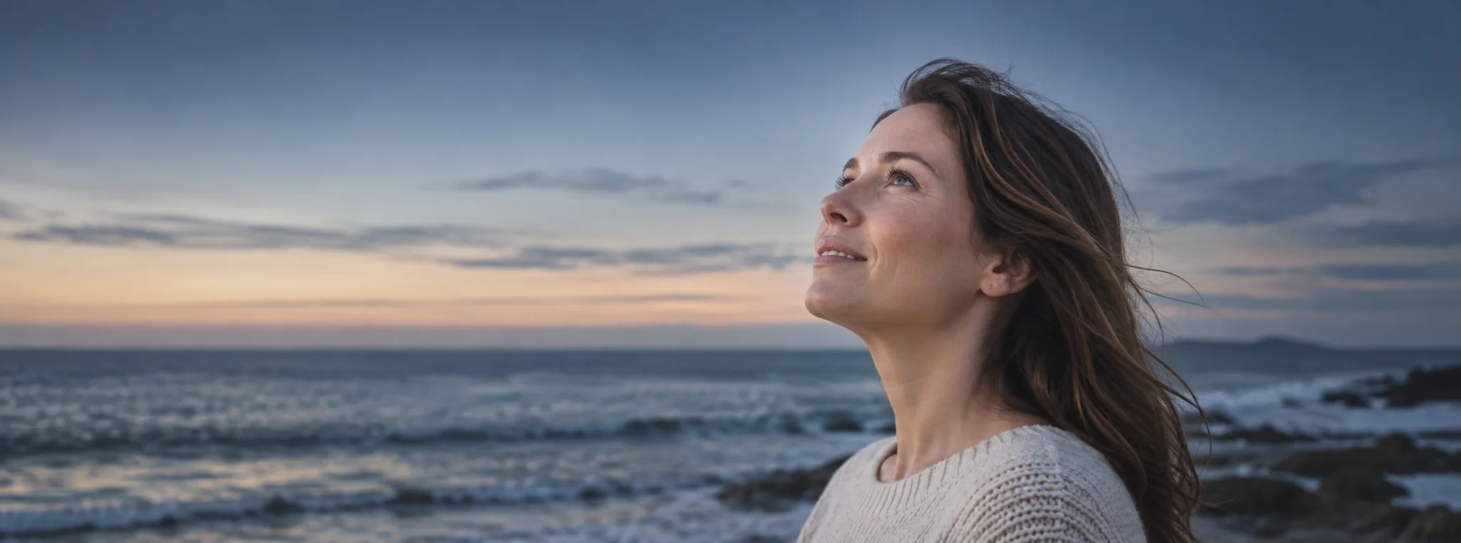 Woman looking toward the sky above the sea at dusk
